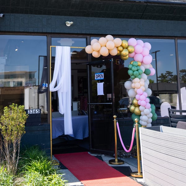 Jamerican Kitchen Cafe entrance with a colorful balloon arch, red carpet, and "OPEN" sign.