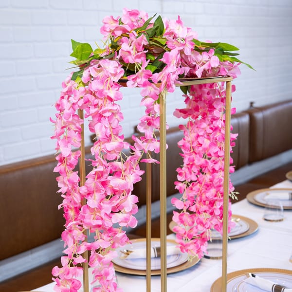 Pink floral centerpiece on a dining table with white tablecloth and place settings at Jamerican Kitchen Cafe.