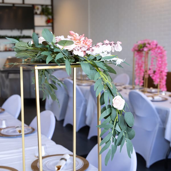 Elegant gold floral centerpiece with pink and white flowers, set on a dining table at Jamerican Kitchen Cafe.